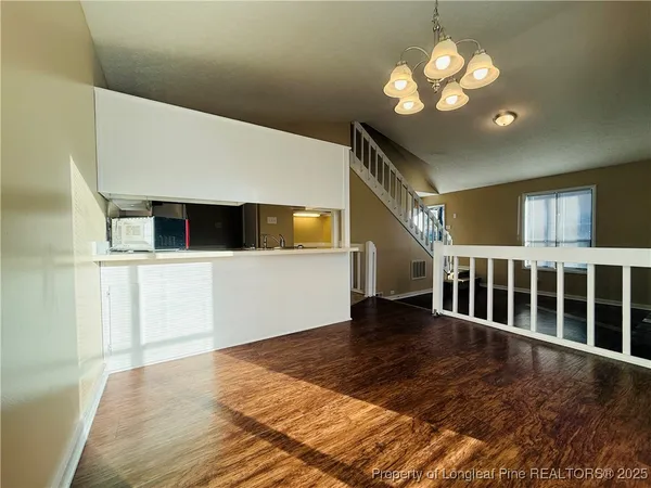 a view of an empty room with wooden floor and windows