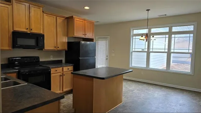 a kitchen with granite countertop a refrigerator and a stove top oven