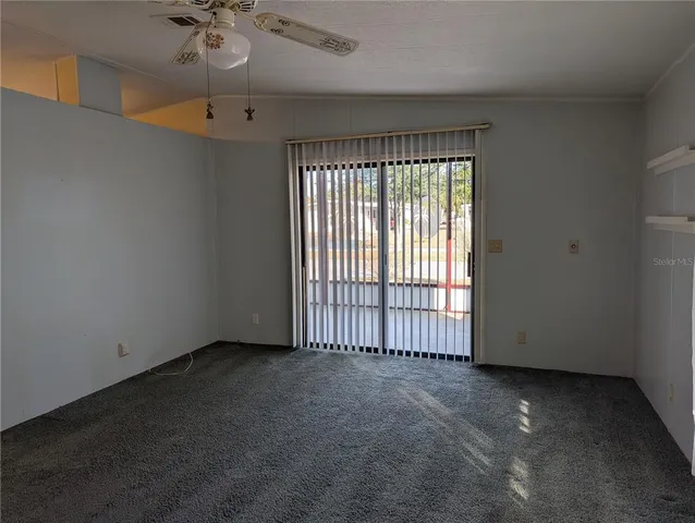 an empty room with a ceiling fan and window