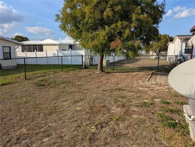 a view of a white house next to a yard with a tree
