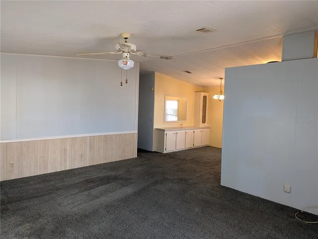 an empty room with wooden floor cabinet and windows