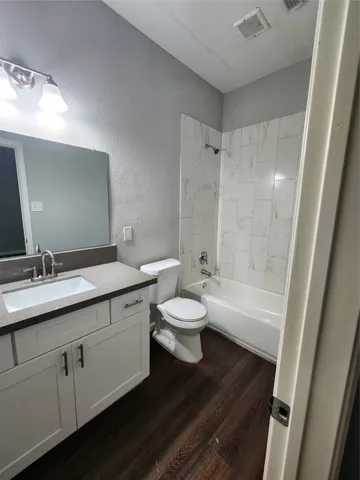 a bathroom with a granite countertop sink toilet a large mirror a bathtub and shower
