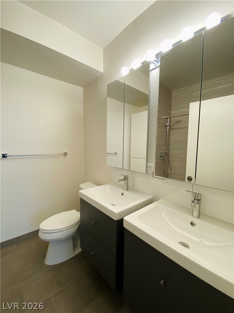 8794 Timber Mesa Street Las Vegas, NV 89139 - Photo 21 of 26 This modern bathroom features twin sinks, sleek cabinetry, and a shower with tile detailing.