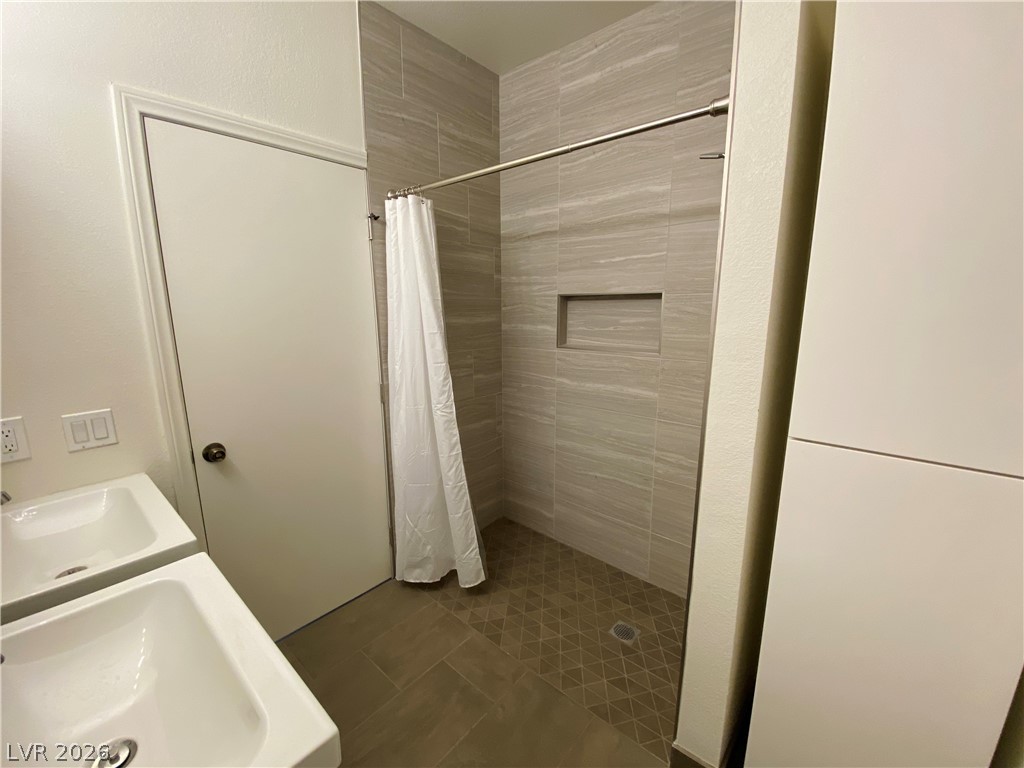8794 Timber Mesa Street Las Vegas, NV 89139 - Photo 23 of 26 This sleek bathroom features dual sinks and a spacious shower, blending both form and function seamlessly.