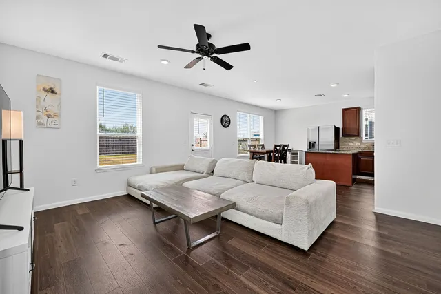a living room with couches and kitchen view with wooden floor