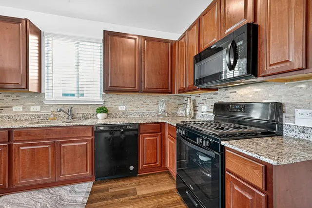 a kitchen with stainless steel appliances granite countertop a stove a sink and a microwave