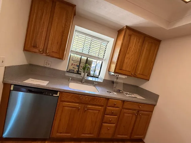 a kitchen with stainless steel appliances granite countertop wooden cabinets a sink and a mirror