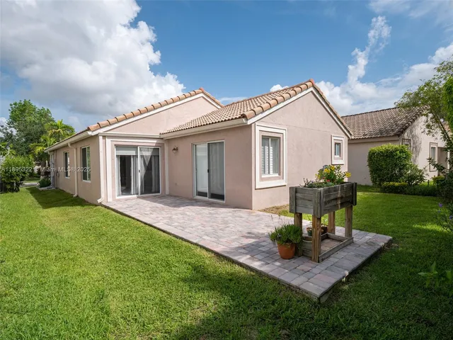 a view of a yard in front of a house with plants and large tree
