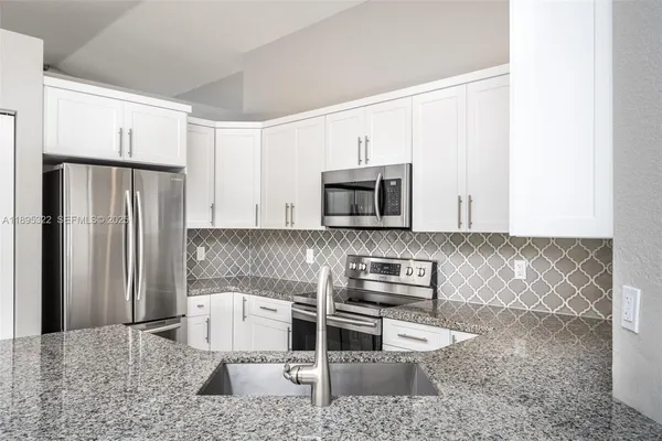 a kitchen with stainless steel appliances granite countertop a refrigerator a stove and a sink
