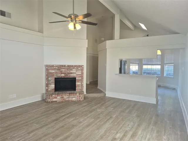 a view of a livingroom with a fireplace a chandelier and wooden floor