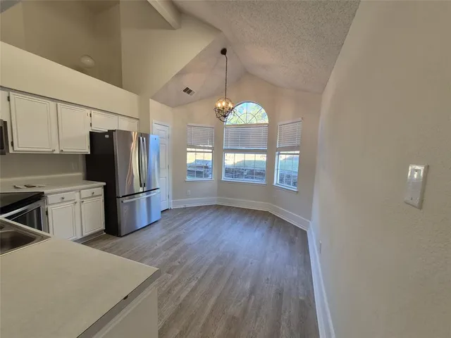 a kitchen with stainless steel appliances granite countertop a refrigerator a sink dishwasher a stove and white countertops with wooden floor