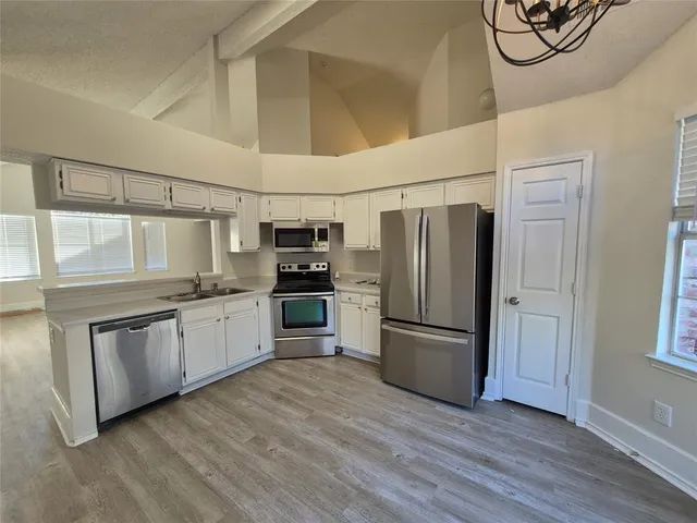 a kitchen with granite countertop stainless steel appliances a refrigerator cabinets and wooden floor