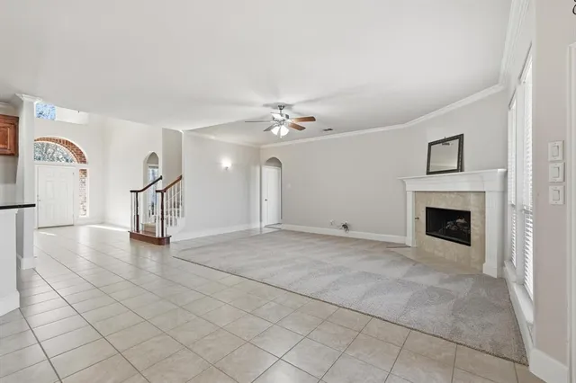 a view of a livingroom with a fireplace a ceiling fan and windows
