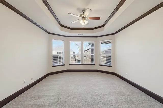 an empty room with chandelier fan and windows