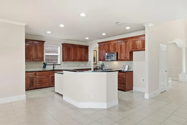 a large kitchen with stainless steel appliances granite countertop a stove refrigerator a sink and dishwasher