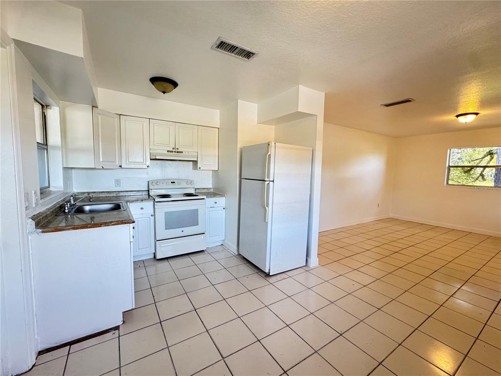 4883 North Pine Hills Road, Unit 4881 Orlando, FL 32808 - Photo 5 of 16 a kitchen with a refrigerator sink and cabinets