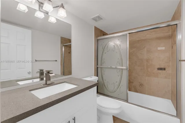 a bathroom with a granite countertop sink a toilet and a shower