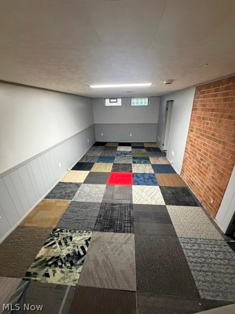 1388 Cranover Road Lyndhurst, OH 44124 - Photo 31 of 35 Exposed brick accent wall, multi-colored carpet tile flooring, window with security bars, painted paneling, and overhead fluorescent lighting