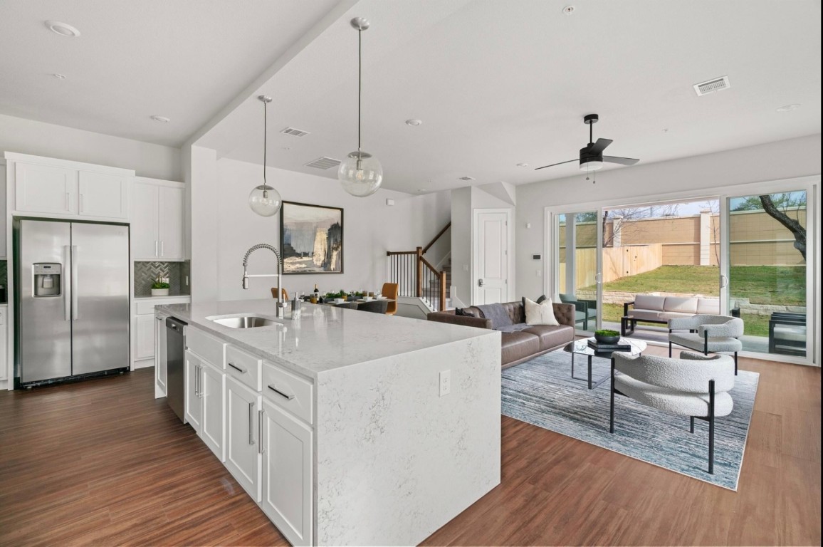 a large white kitchen with kitchen island a large island a sink stainless steel appliances and wooden floor