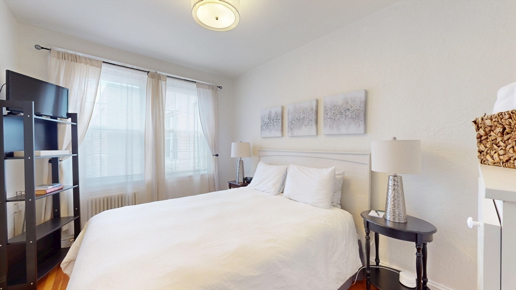 90 Kilsyth Road, Unit 43 Boston, MA 02135 - Photo 5 of 8 a bedroom with a bed and a chandelier