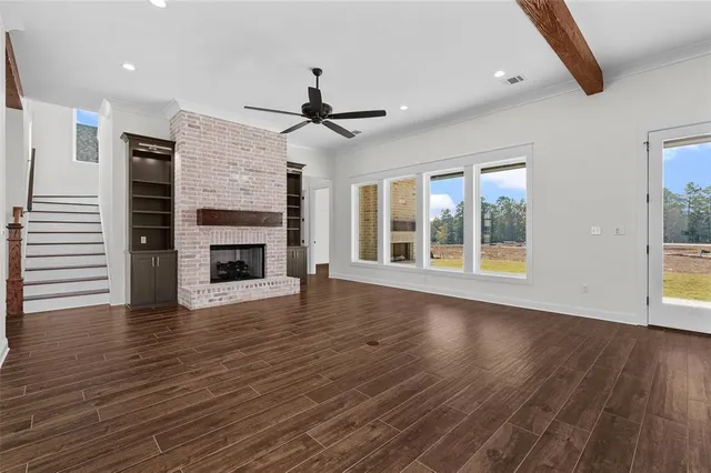 a view of an empty room with wooden floor fireplace and a window
