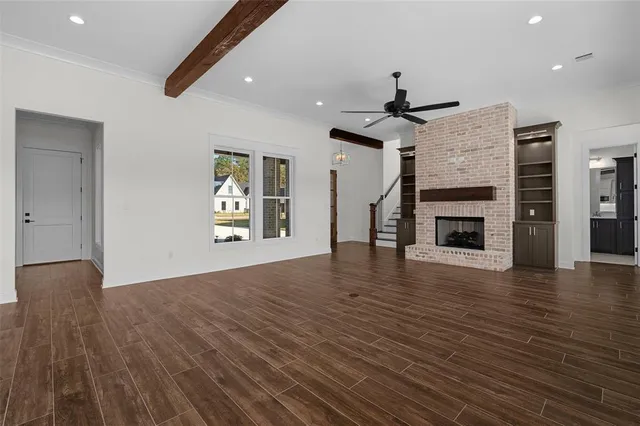 a view of an empty room with wooden floor fireplace and a window