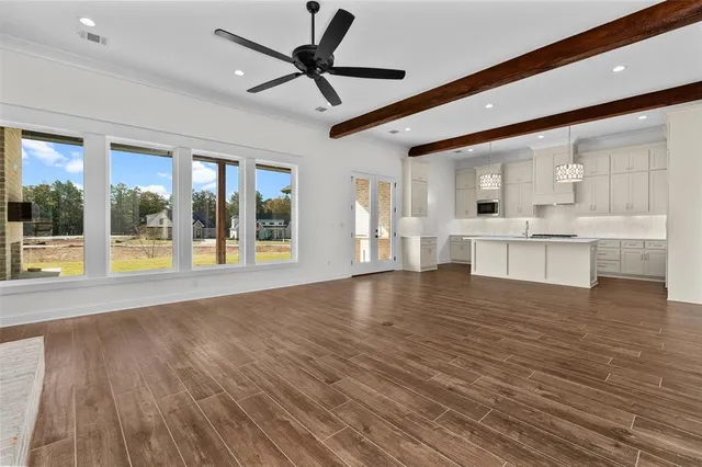 a view of an empty room with window and wooden floor