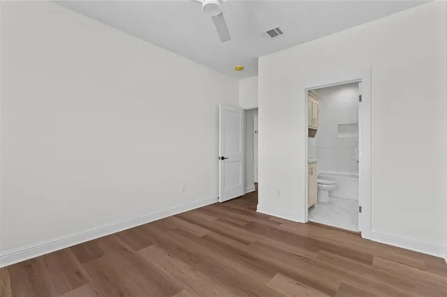 an empty room with wooden floor cabinet and windows