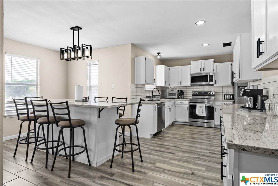 a kitchen with stainless steel appliances granite countertop wooden floor dining table and chairs