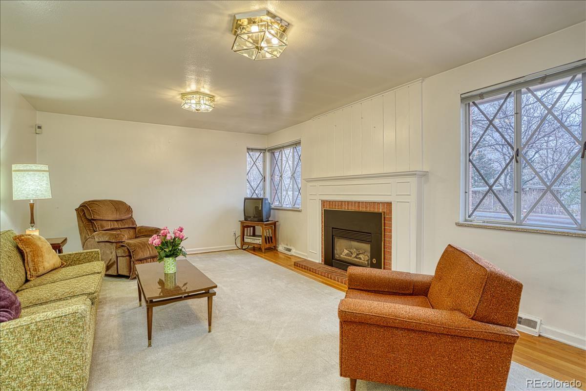 1279 West Ridge Road Littleton, CO 80120 - Photo 3 of 16 a living room with furniture a chandelier and a fireplace