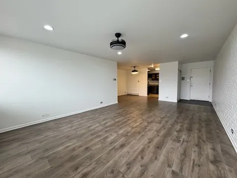 an empty room with wooden floor ceiling fan and windows