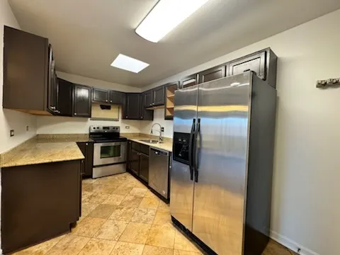 a kitchen with stainless steel appliances a refrigerator a stove a sink and dishwasher