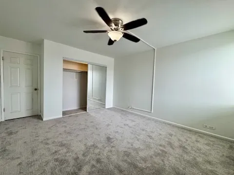 an empty room with closet and ceiling fan