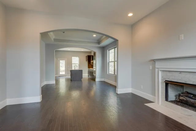 an empty room with wooden floor fireplace and windows