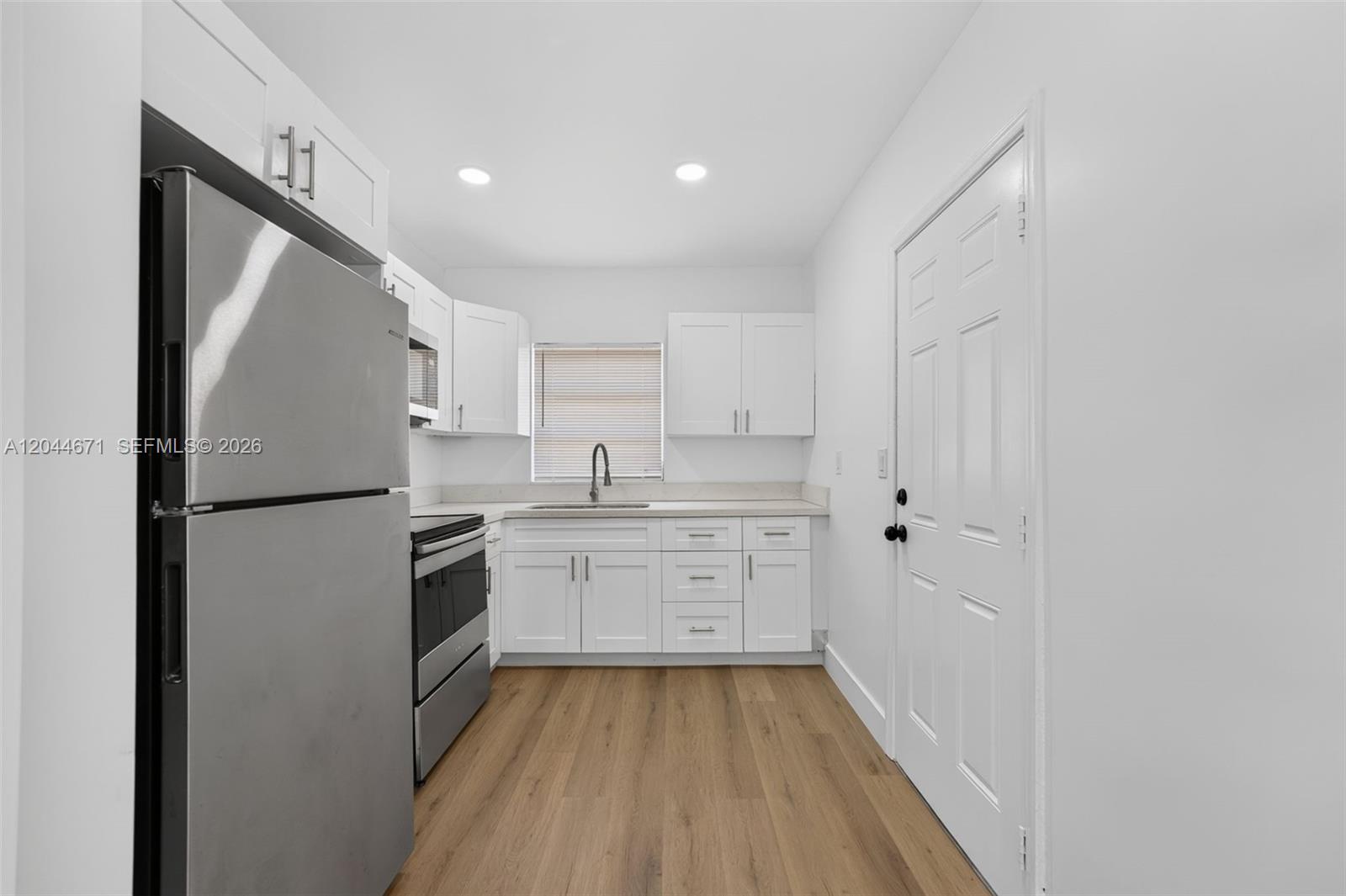 1900 Southwest 6th Street, Unit 6 Miami, FL 33135 - Photo 4 of 20 a kitchen with white cabinets and stainless steel appliances
