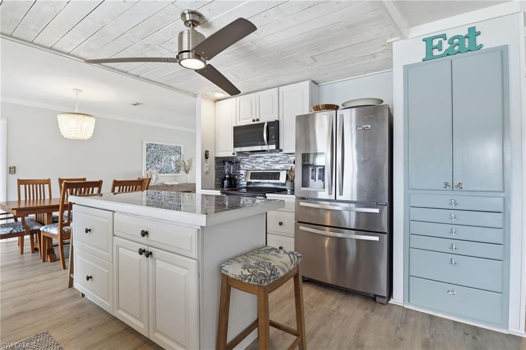 2211 Bayview Road Punta Gorda, FL 33950 - Photo 22 of 37 Kitchen featuring appliances with stainless steel finishes, wooden ceiling, white cabinets, backsplash, and a center island