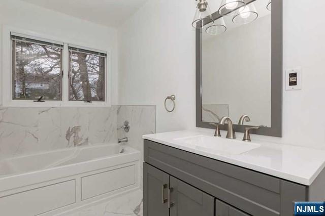 135 7th Street Cresskill, NJ 07626 - Photo 11 of 17 a bathroom with a sink and a bathtub next to a window