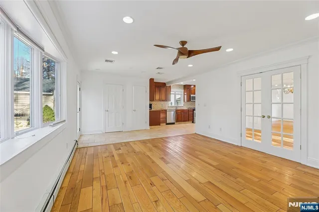 a view of empty room with wooden floor and fan