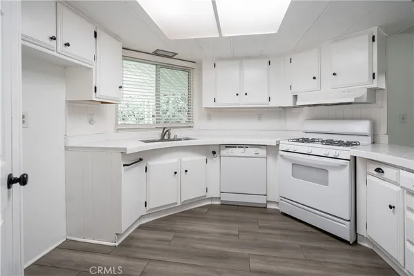 a kitchen with white cabinets appliances a sink and a window