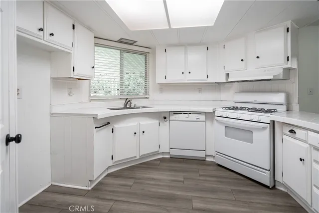 a kitchen with white cabinets appliances a sink and a window