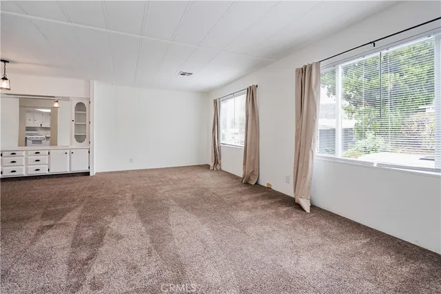 an empty room with windows and view of bathroom