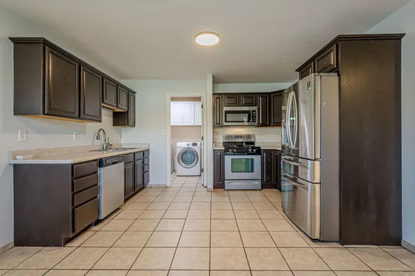 a kitchen with a refrigerator sink and wooden cabinets