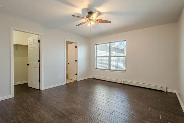 an empty room with wooden floor chandelier fan and windows