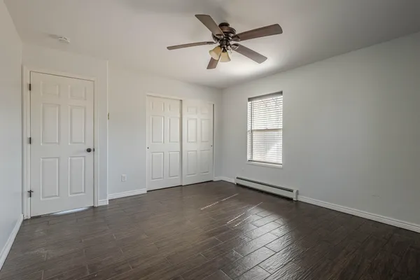 a view of empty room with wooden floor and fan