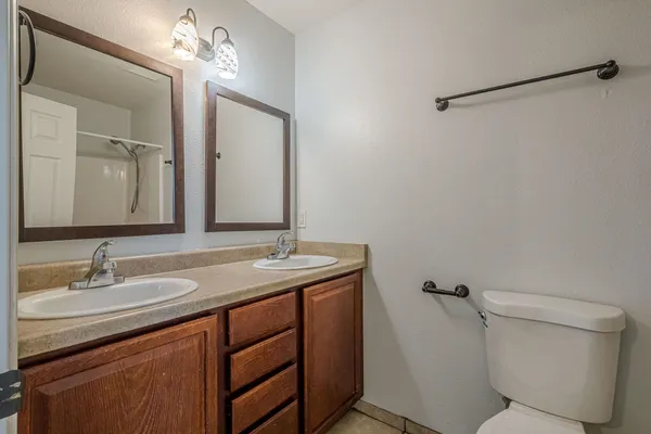 a bathroom with a granite countertop sink toilet and mirror