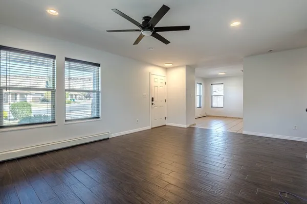 a view of an empty room with wooden floor and a window
