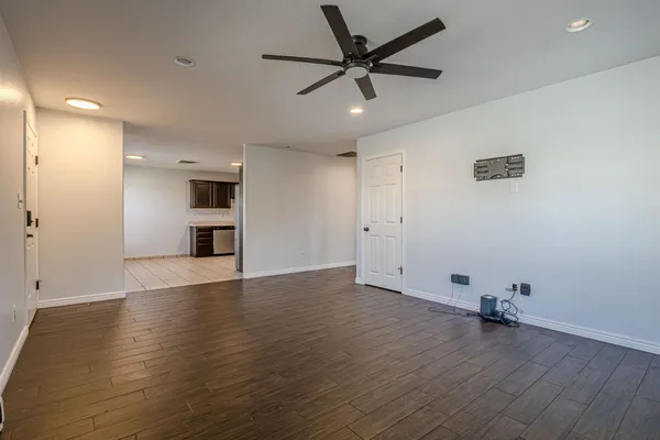 an empty room with wooden floor and a ceiling fan
