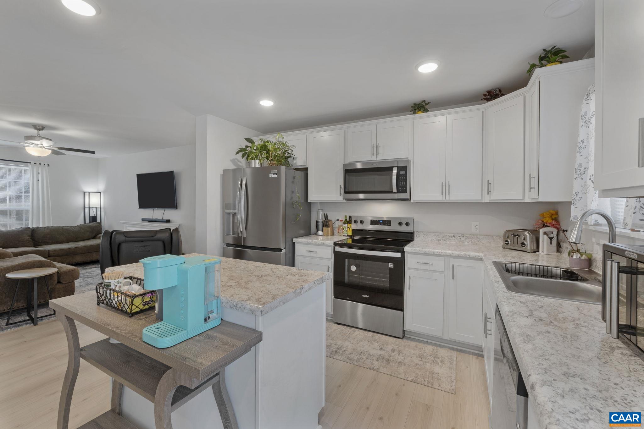 7440 Louisa Road Gordonsville, VA 22942 - Photo 15 of 40 a kitchen with stainless steel appliances granite countertop a stove top oven a sink dishwasher a dining table and chairs with wooden floor