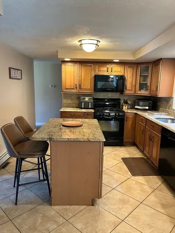 a kitchen with stainless steel appliances granite countertop a stove top oven a sink a dining table and chairs