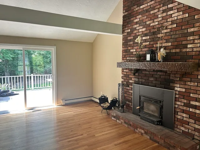 an empty room with wooden floor fireplace and windows